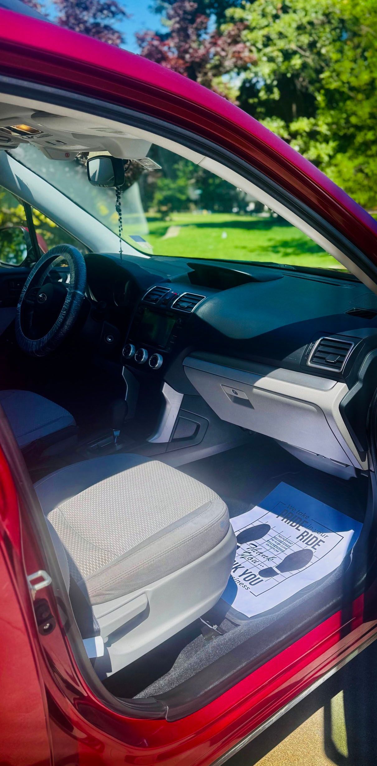 Interior view of a red car, showing the dashboard, driver's seat, and a window.