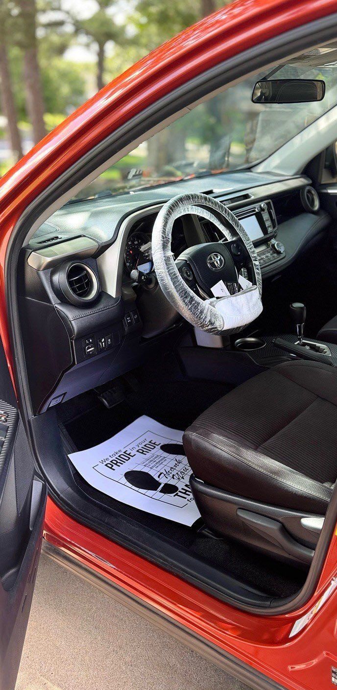 Interior of a red Toyota RAV4, with the door open, showing the steering wheel and driver's seat.