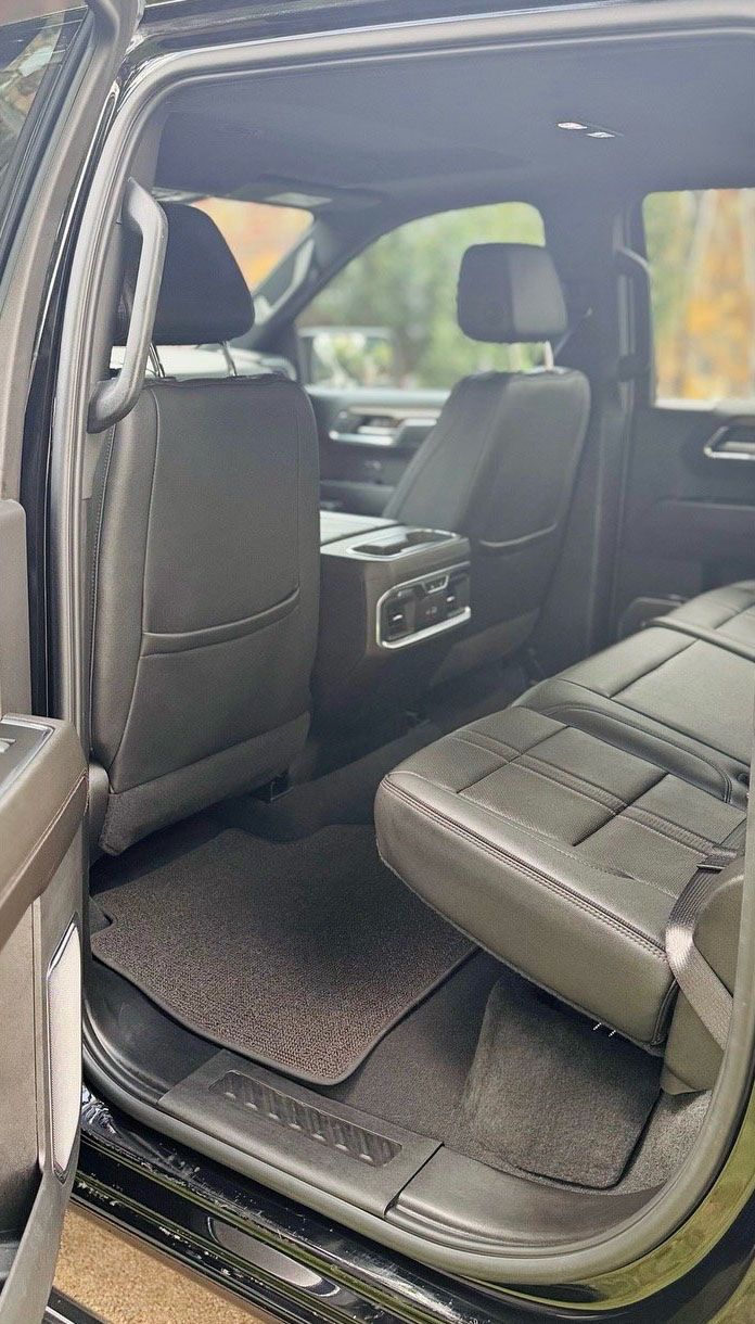 Black truck interior with rear seats, a center console, and black floor mats.