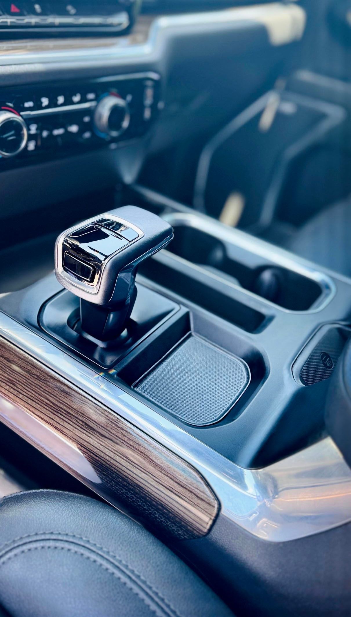 Interior car console with gear shift lever, black and chrome accents, wood trim.