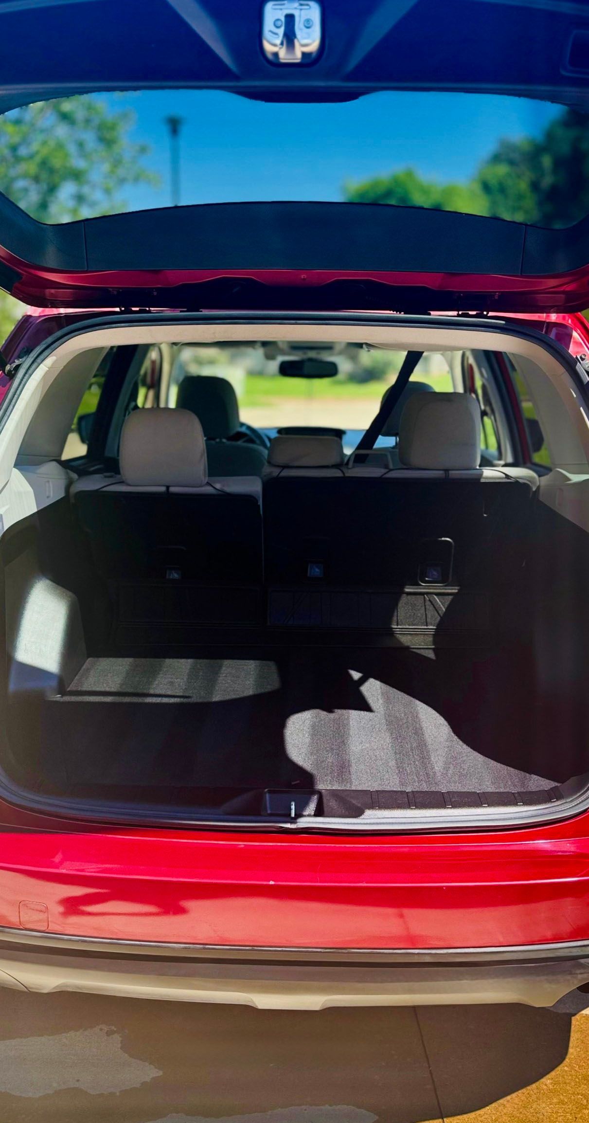 Open red car trunk with folded seats.