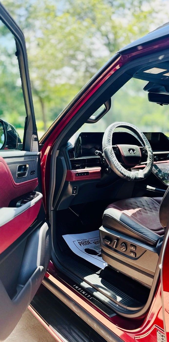 Interior of a red car with the door open, showing the steering wheel and seats.