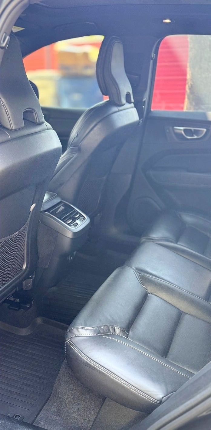 Interior back seat of a car. Black leather seats with headrests and center console.