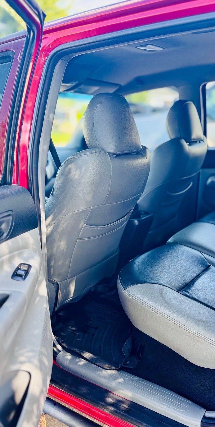 Interior of a red pickup truck with two gray and black leather seats visible. Door is open.