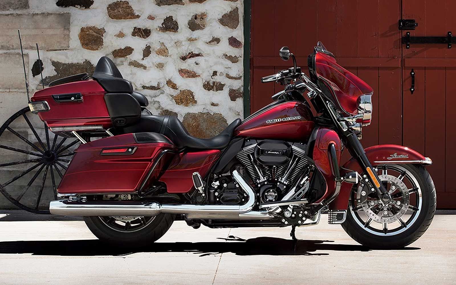 Red Harley-Davidson motorcycle parked in front of a stone wall and wooden door.