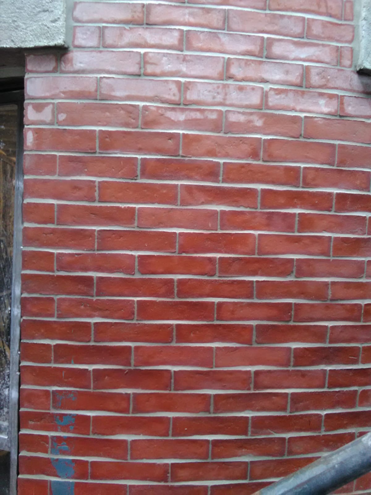 A close up of a red brick wall with a window