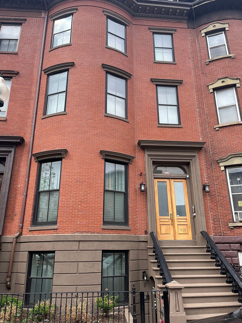 Red brick townhouse with wood door and steps.