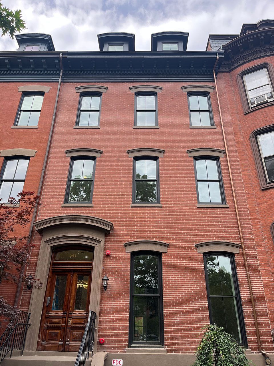 Red brick townhouse with multiple windows and a dark wood door.