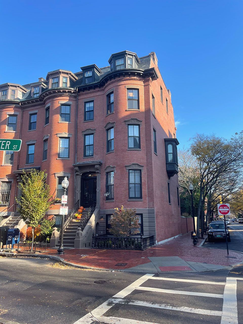 Red brick multi-story building on a city street. Corner location, stairs to entrance. 