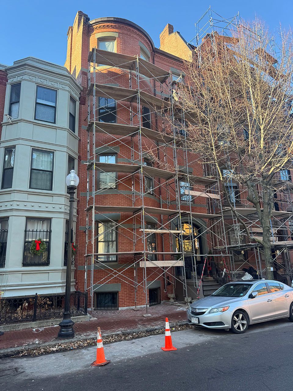 Red brick building with scaffolding; car and street in front.