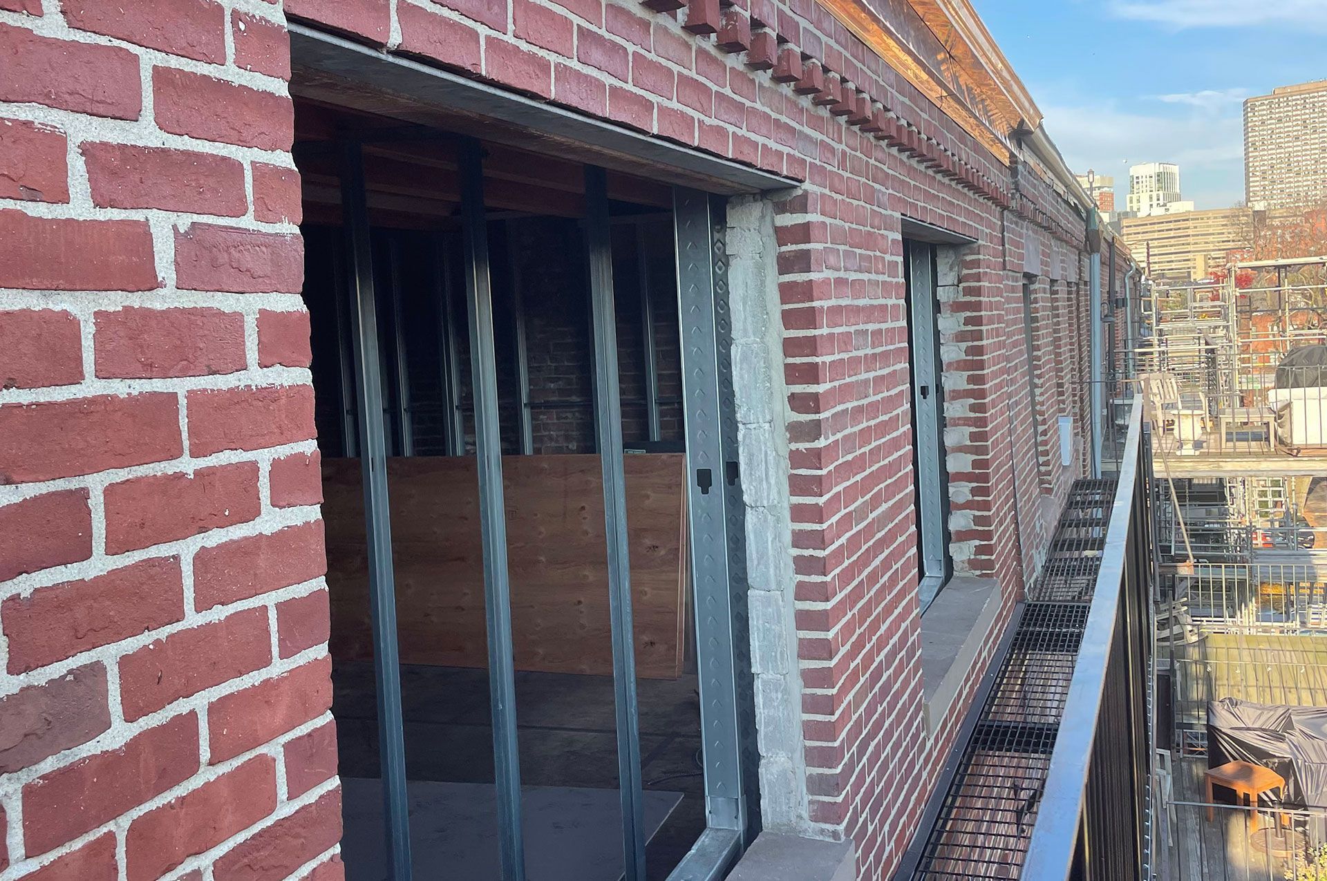 Red brick building with barred windows, city view in the background.