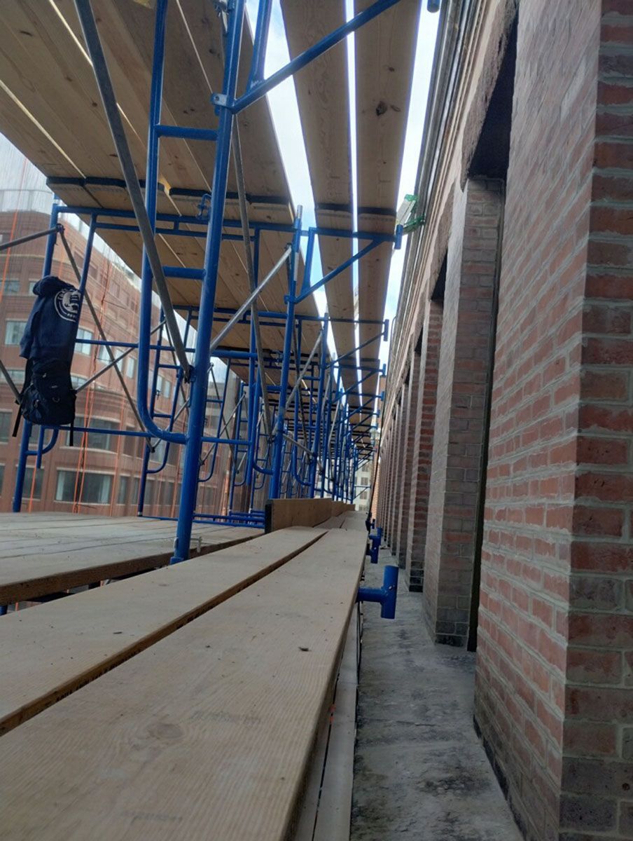 A row of blue scaffolding along a brick building