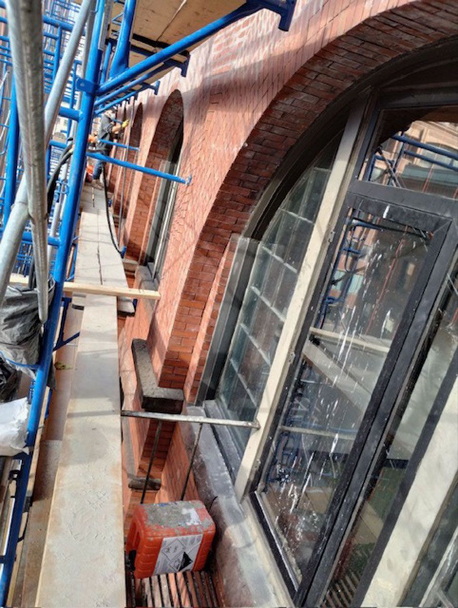 A brick building with arched windows and scaffolding around it