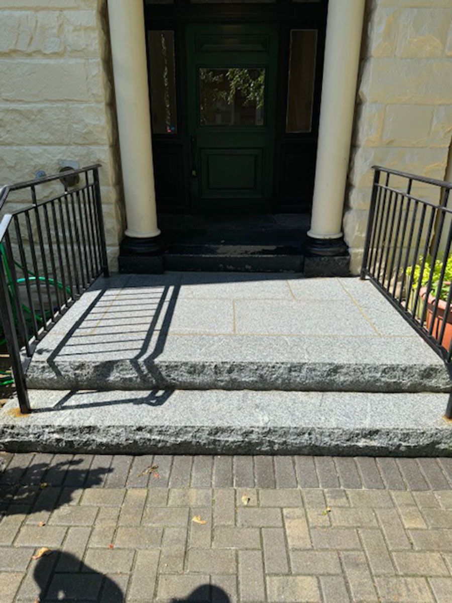 A brick walkway with stairs leading up to a green door