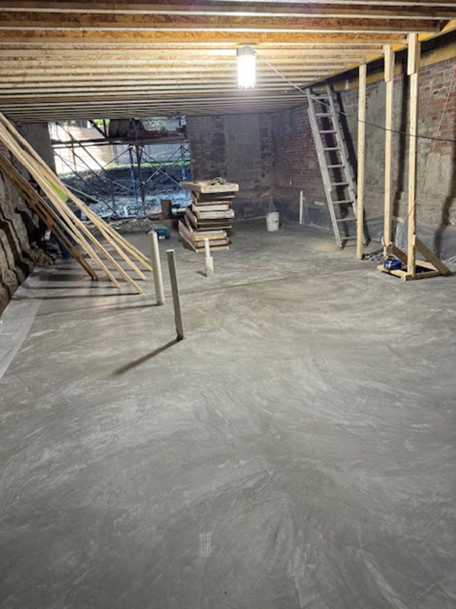 A basement under construction with a ladder and wooden beams
