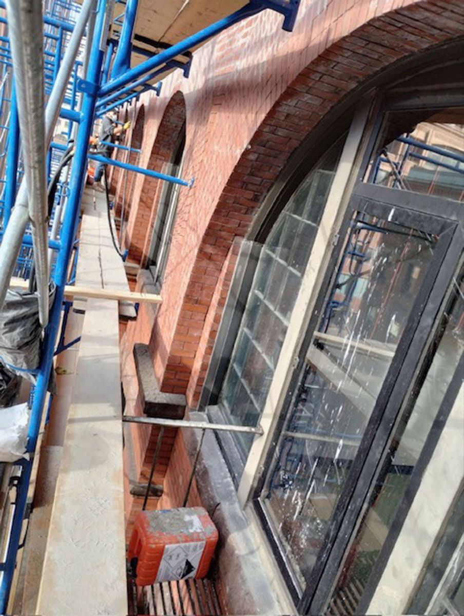 A brick building with arched windows is being built with scaffolding