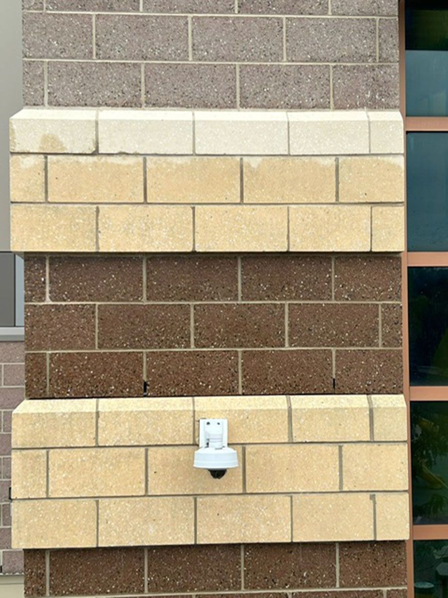 A security camera is mounted on the side of a brick building