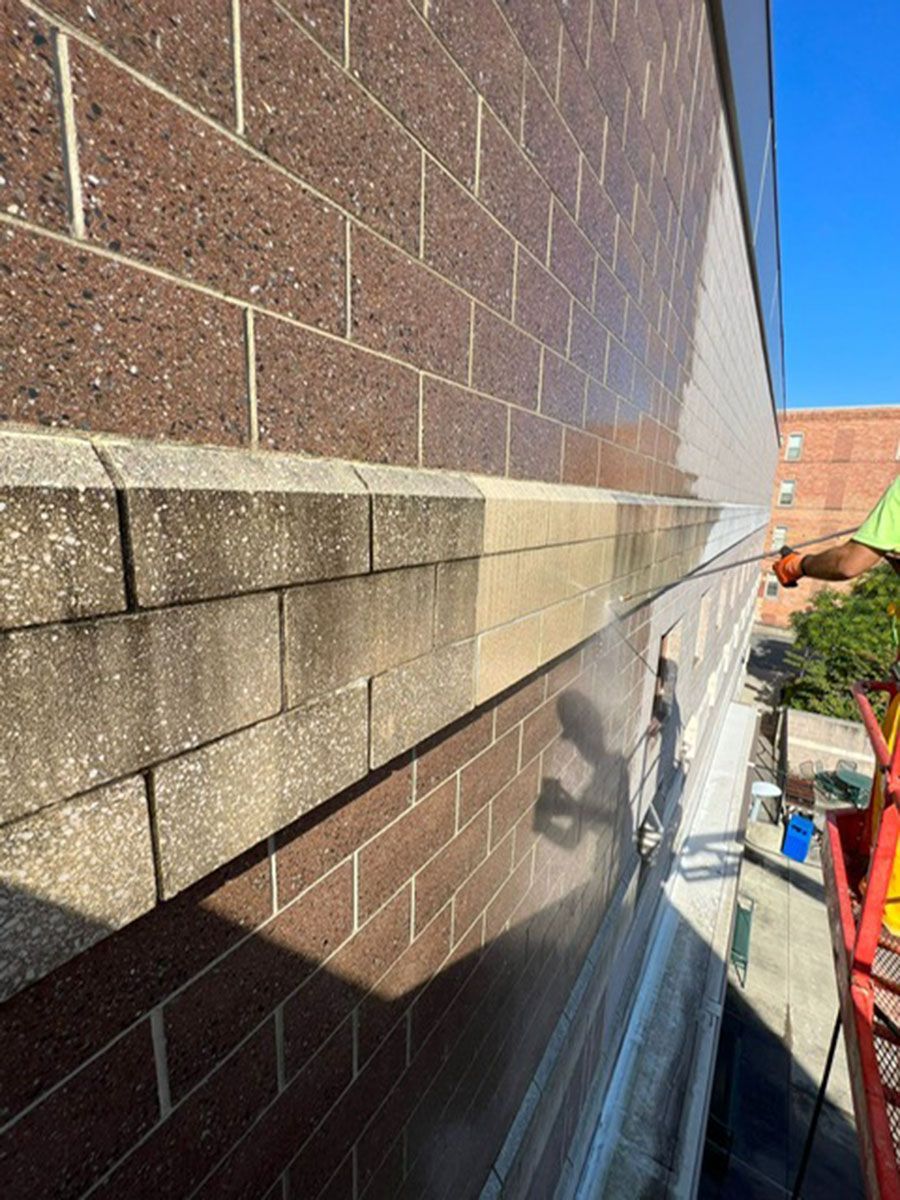 A man is cleaning a brick wall with a pressure washer