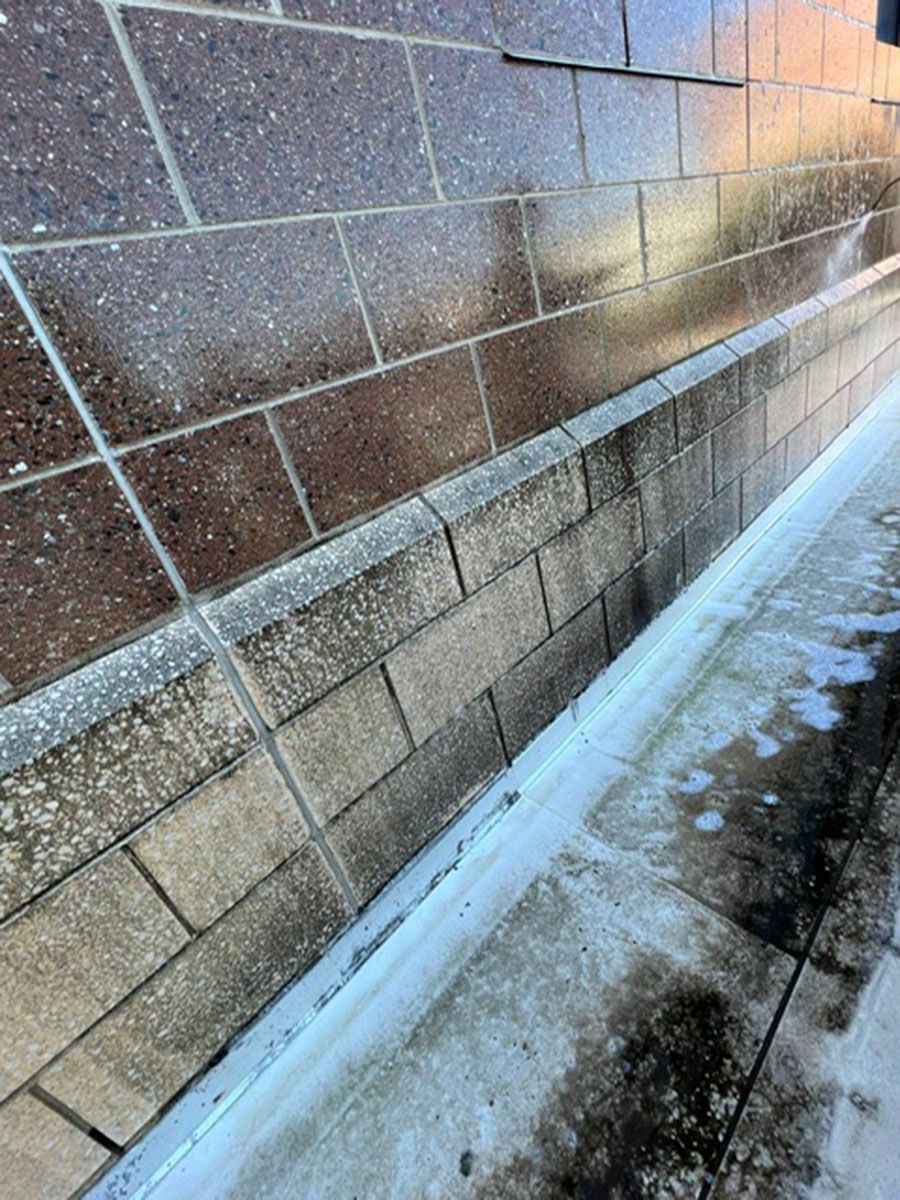 A brick wall is being cleaned with a pressure washer