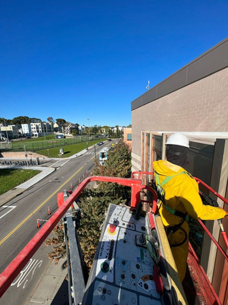 A man is standing on a crane on top of a building