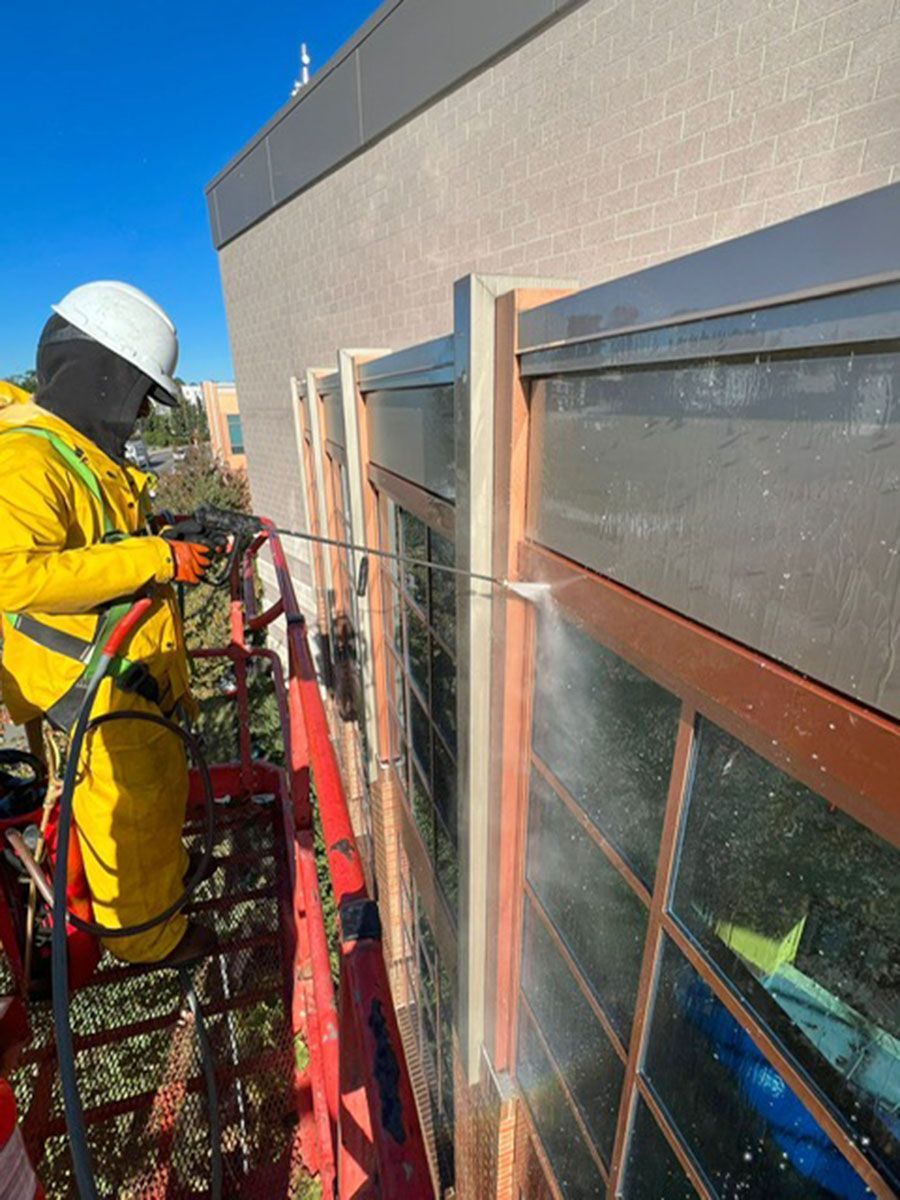 A man is cleaning a building with a high-pressure washer