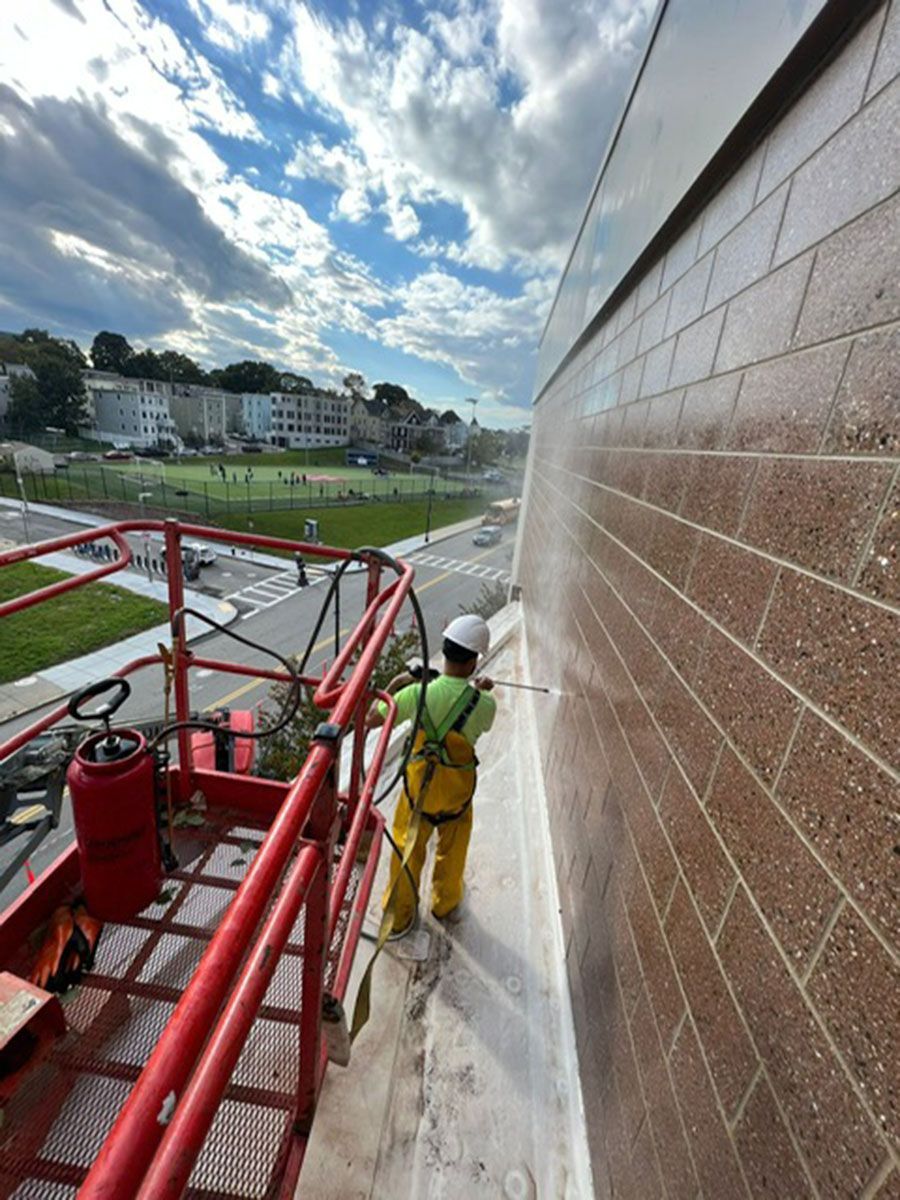 A man is spraying a brick wall with a hose
