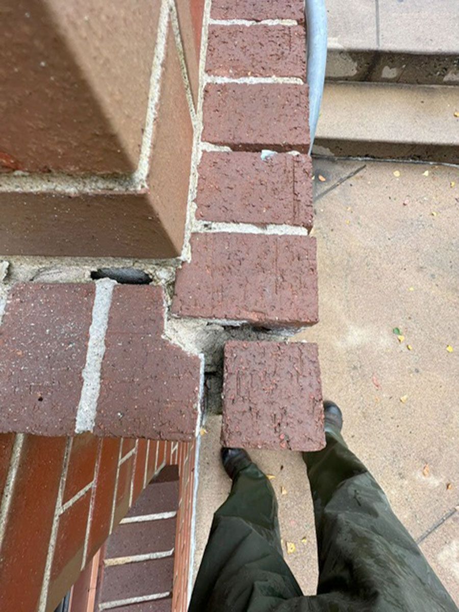A person is standing next to a brick wall