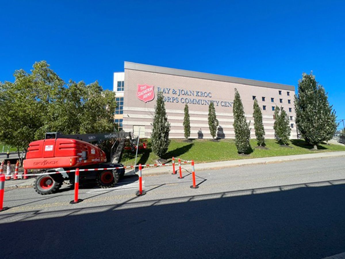A red excavator is parked in front of a large building