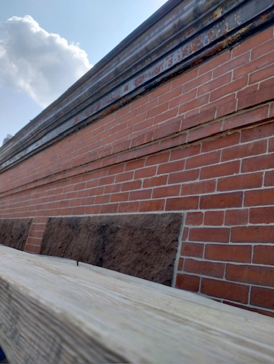 A brick wall with a wooden beam in front of it