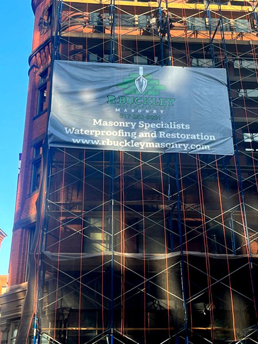 A building with scaffolding and a sign that says masonry specialists waterproofing and restoration
