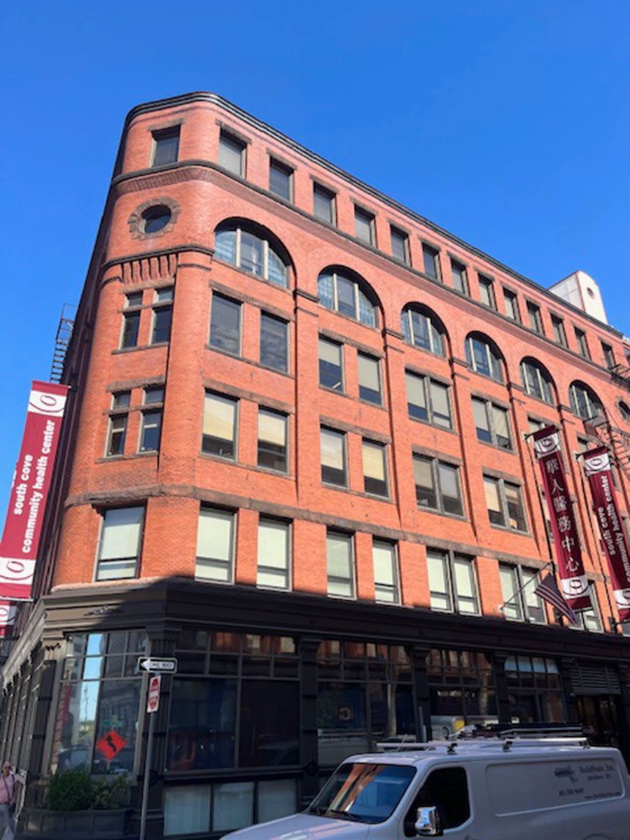 A white van is parked in front of a large brick building
