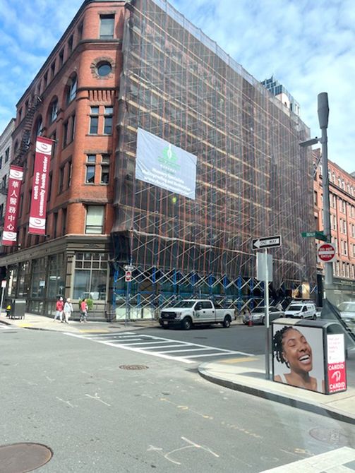 A truck is parked in front of a building that is covered in scaffolding