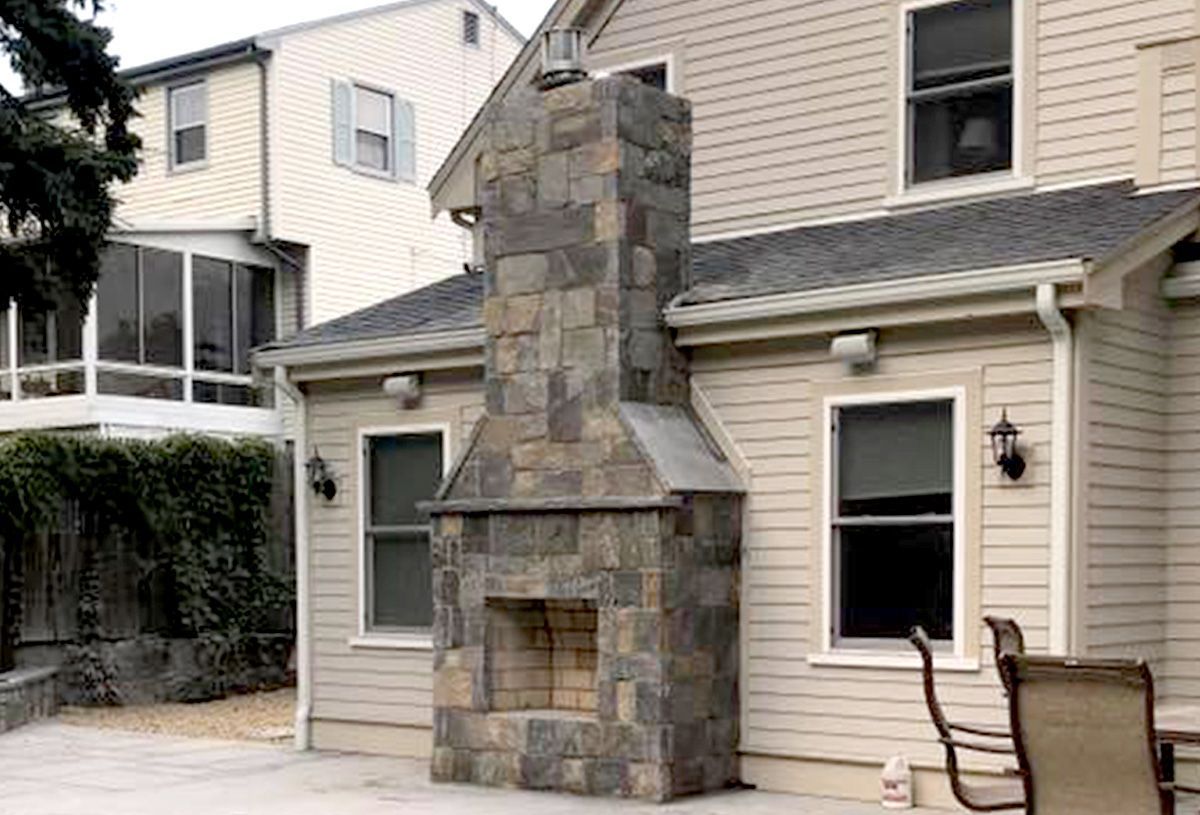 A large stone fireplace is on the side of a house