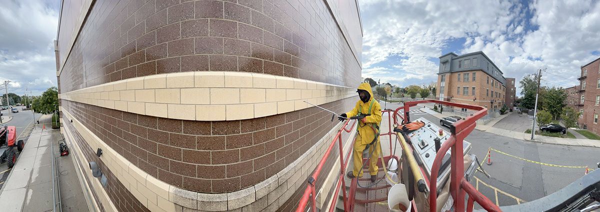 A man is cleaning a brick wall on a crane