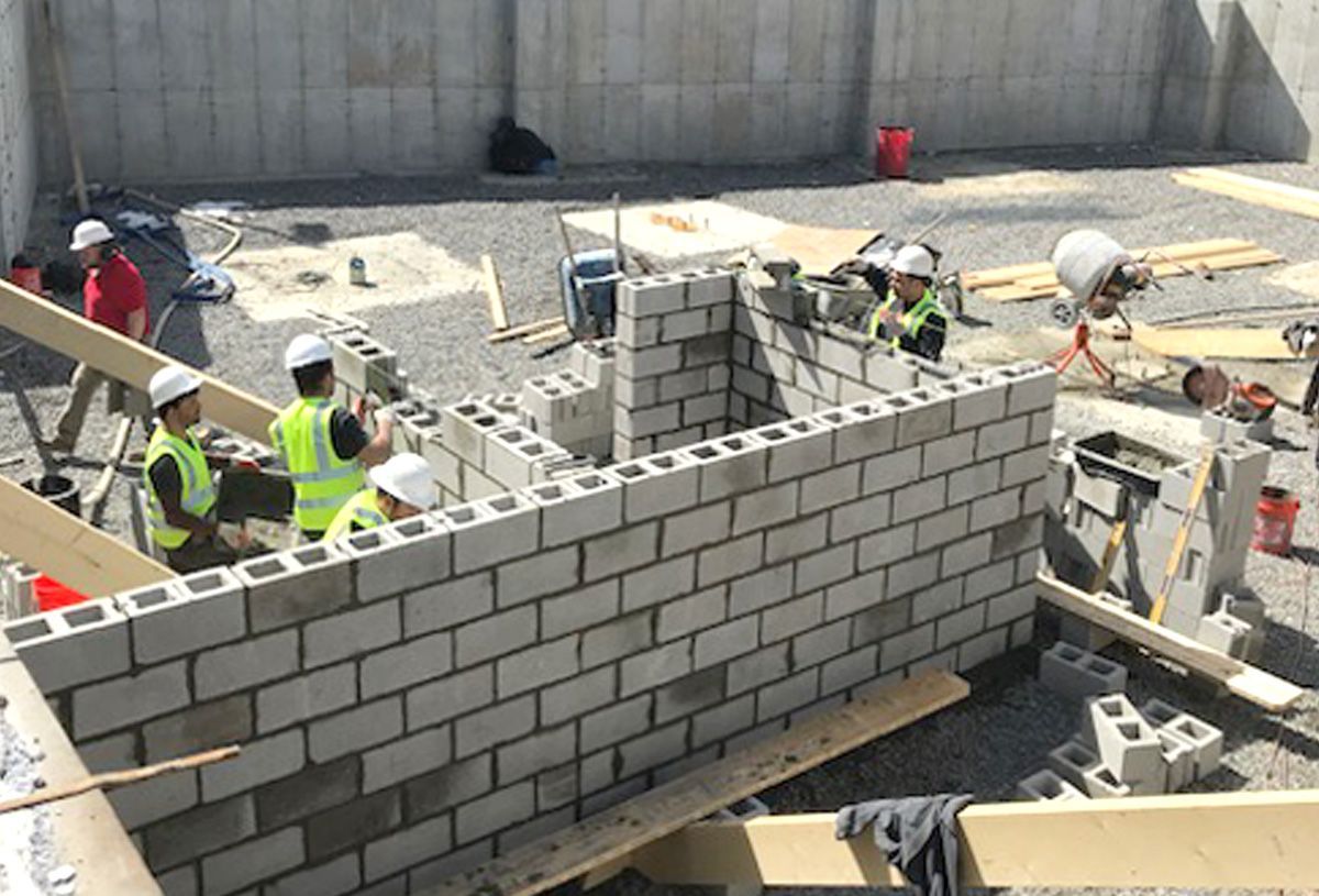 A group of construction workers are working on a brick wall