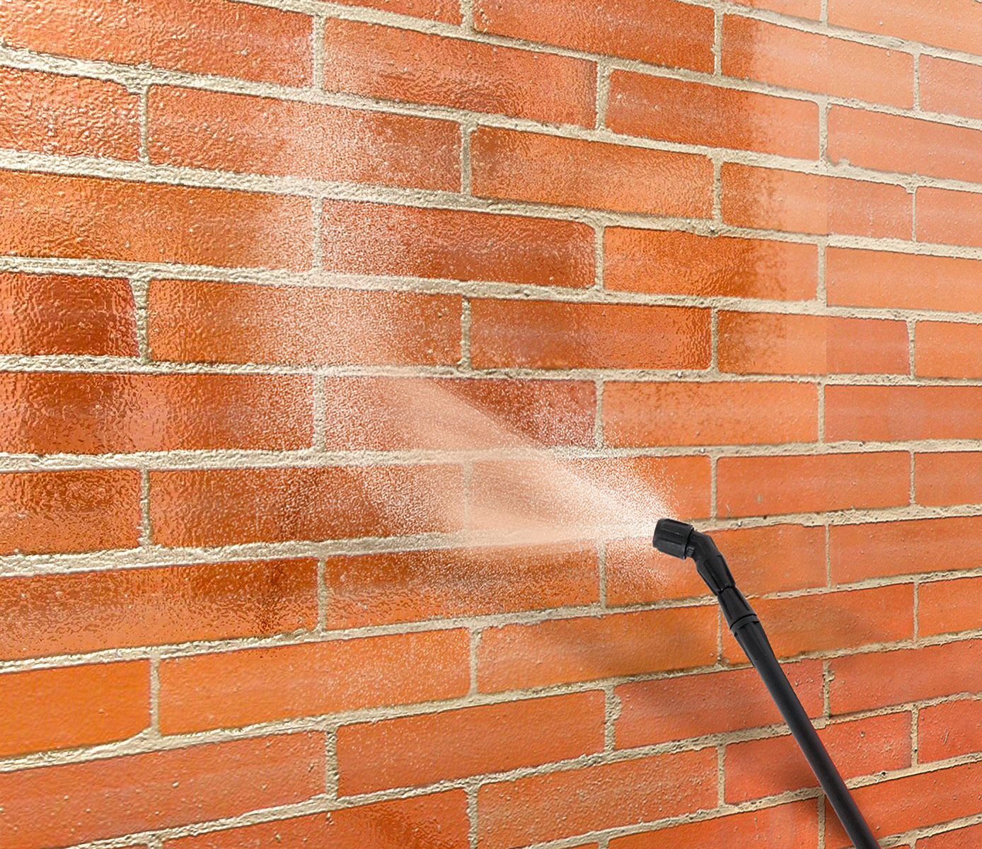 Pressure washer spraying water onto a red brick wall.