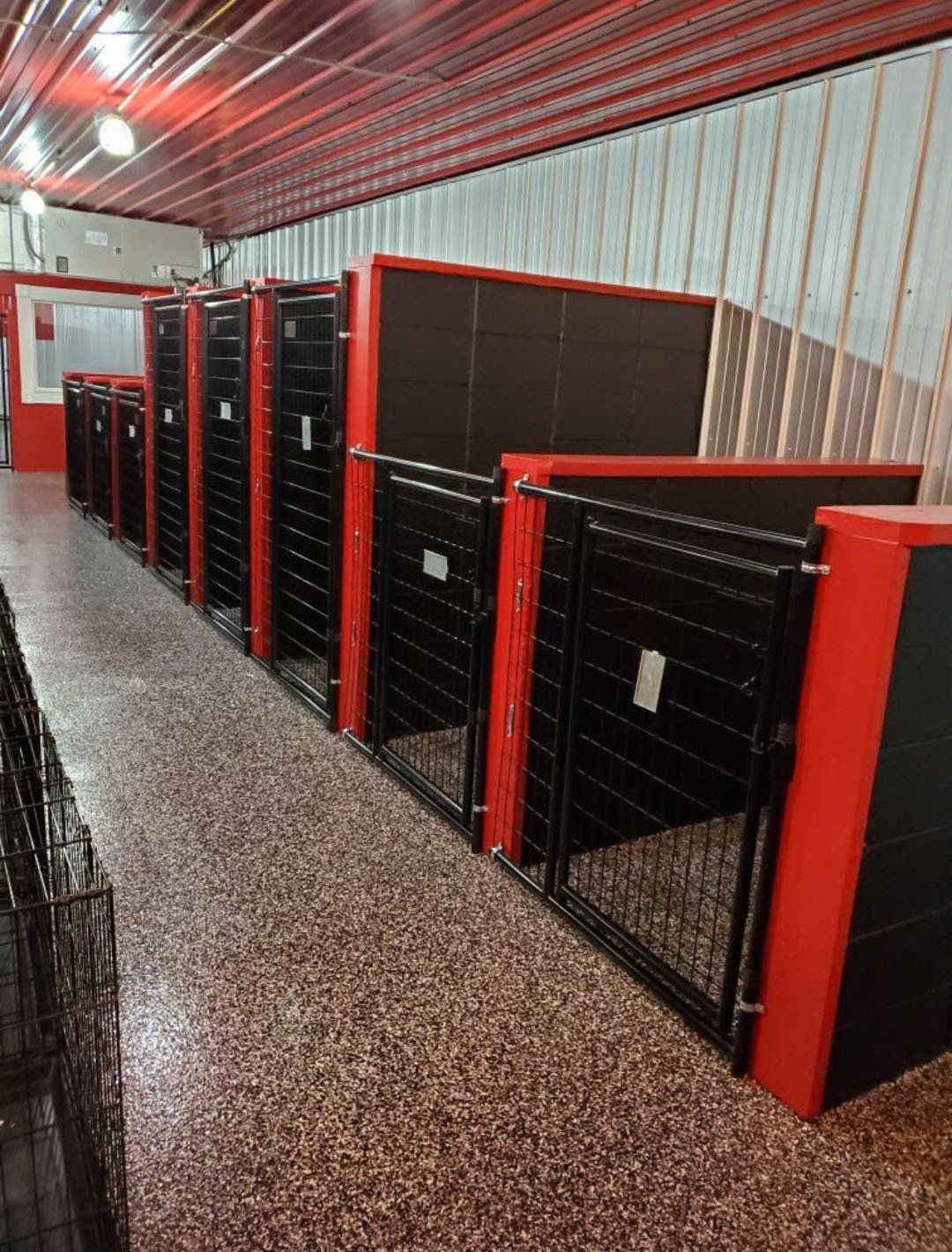 A row of black and red dog kennels in a building.