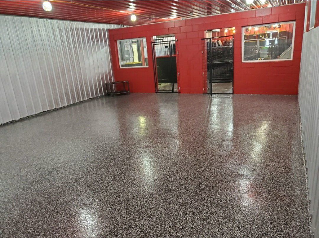 A large room with a concrete floor and a red wall.