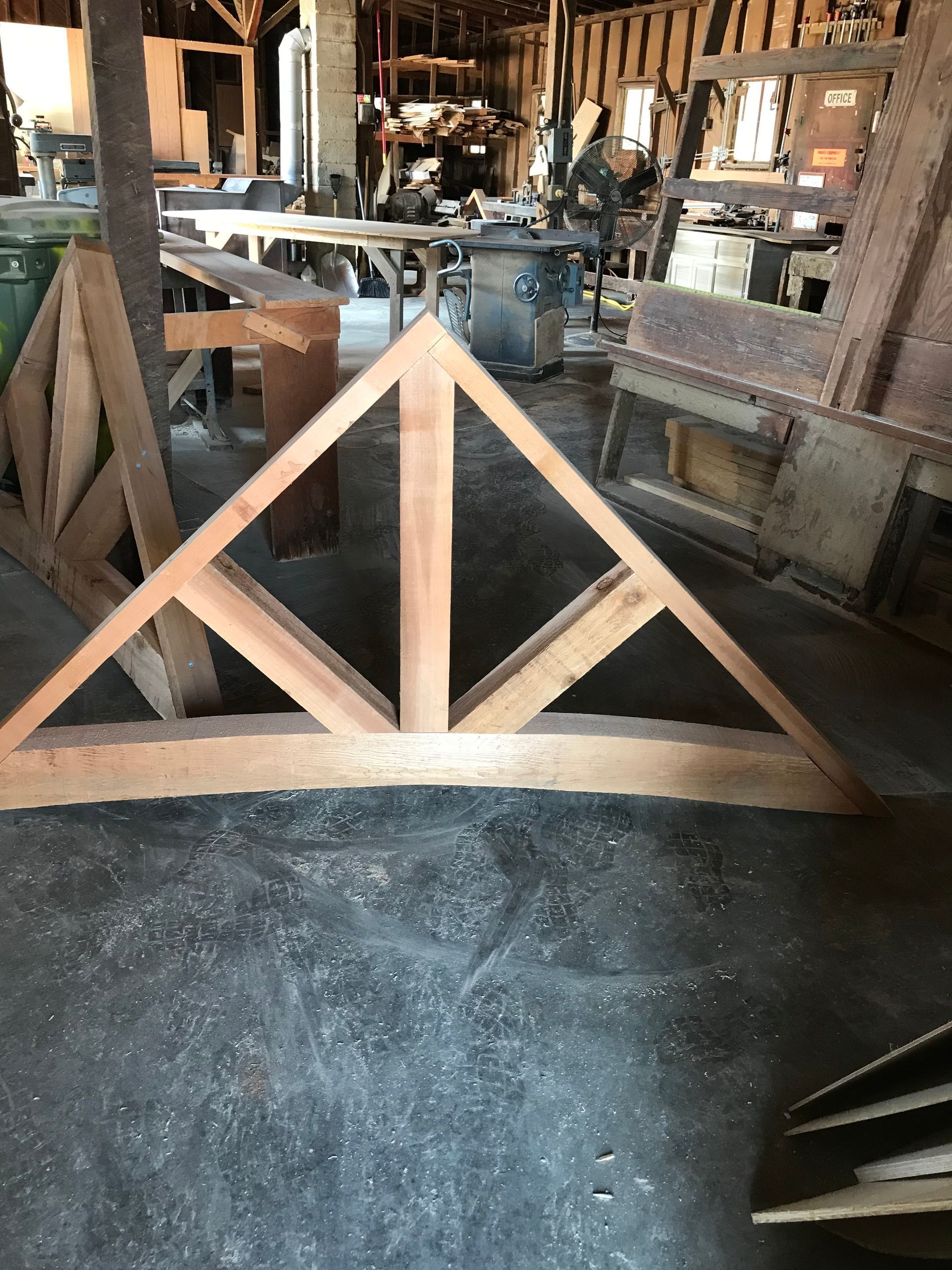Wooden triangular frame in a rustic workshop with tools and machinery in the background