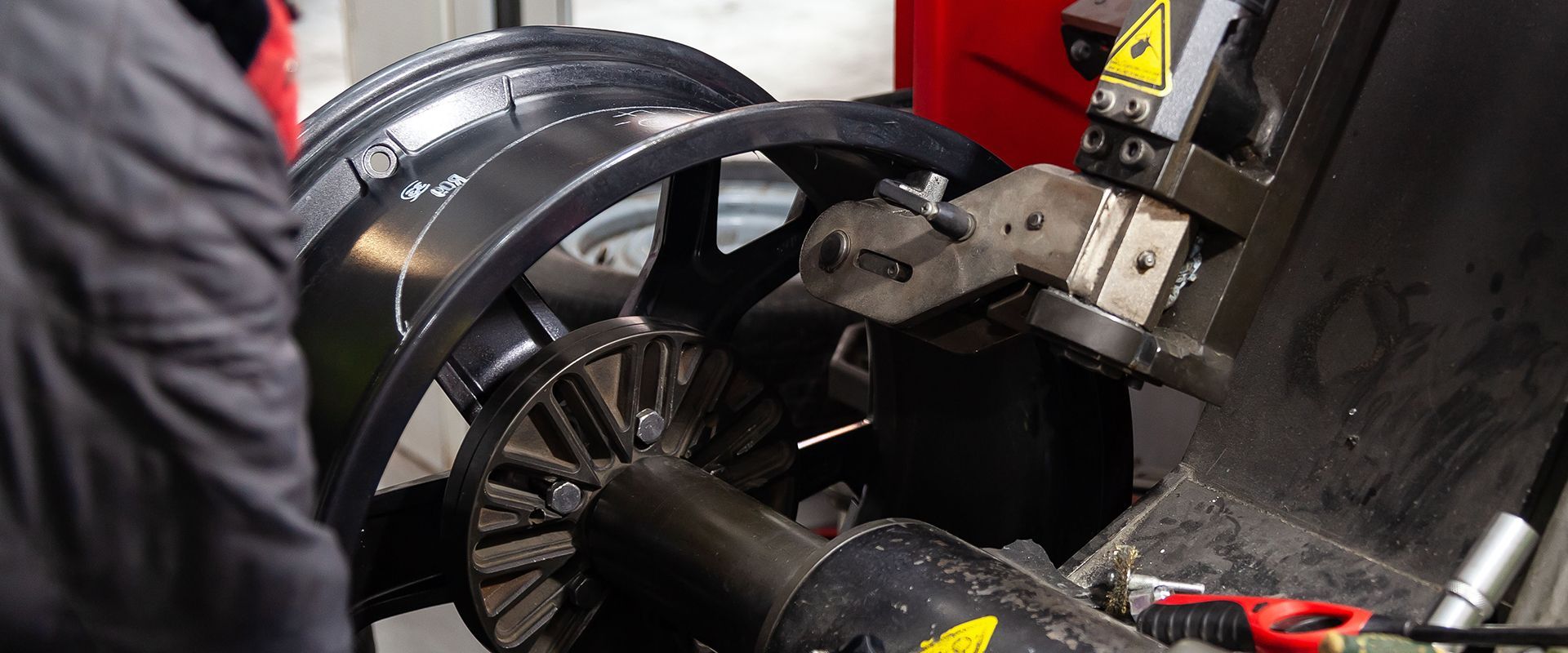 A man is performing maintenance on a rotating machine tire.