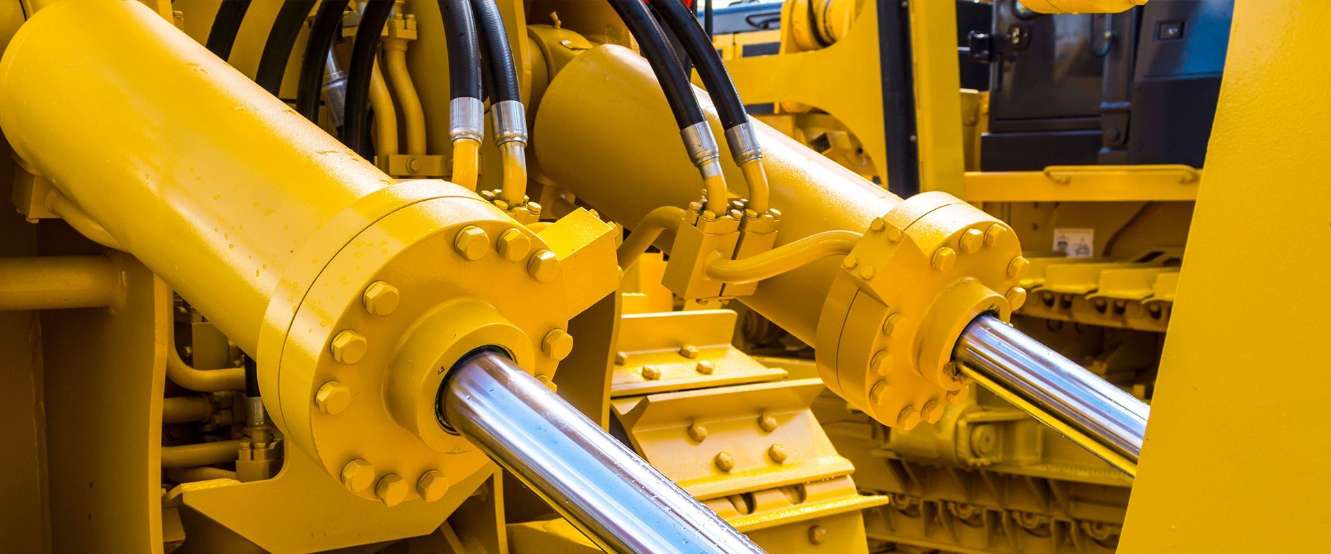 A close up of a yellow hydraulic cylinder on a machine.