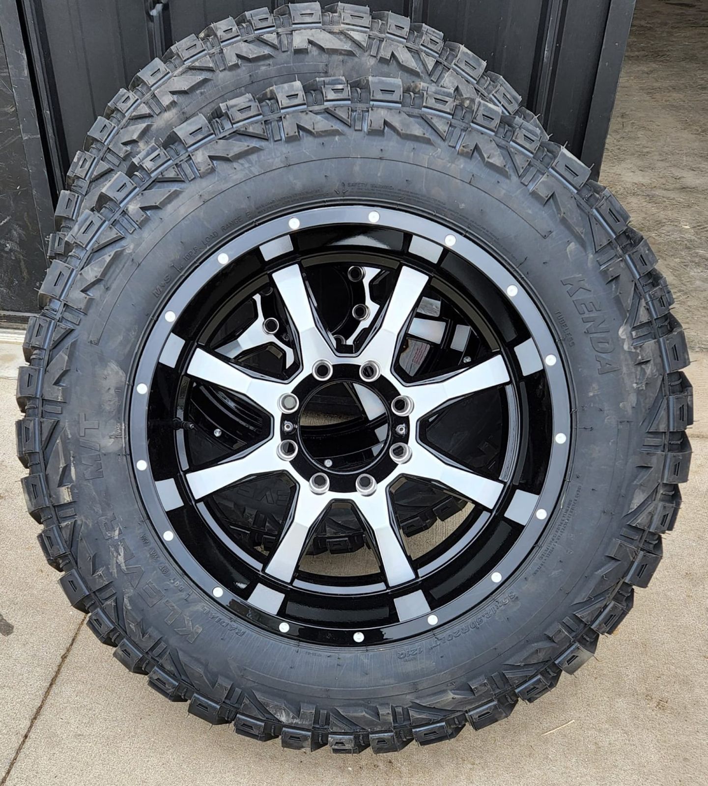 A close up of a tire and wheel on a sidewalk.