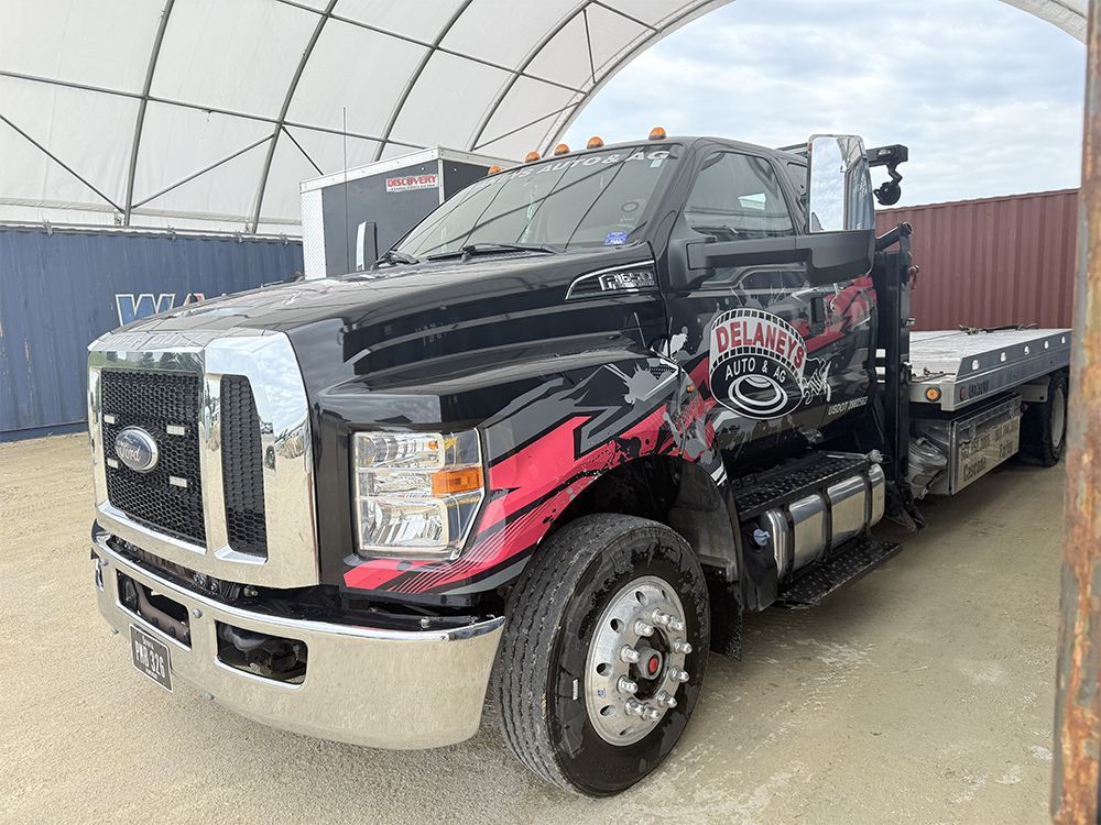 A black and red tow truck is parked under a tent.