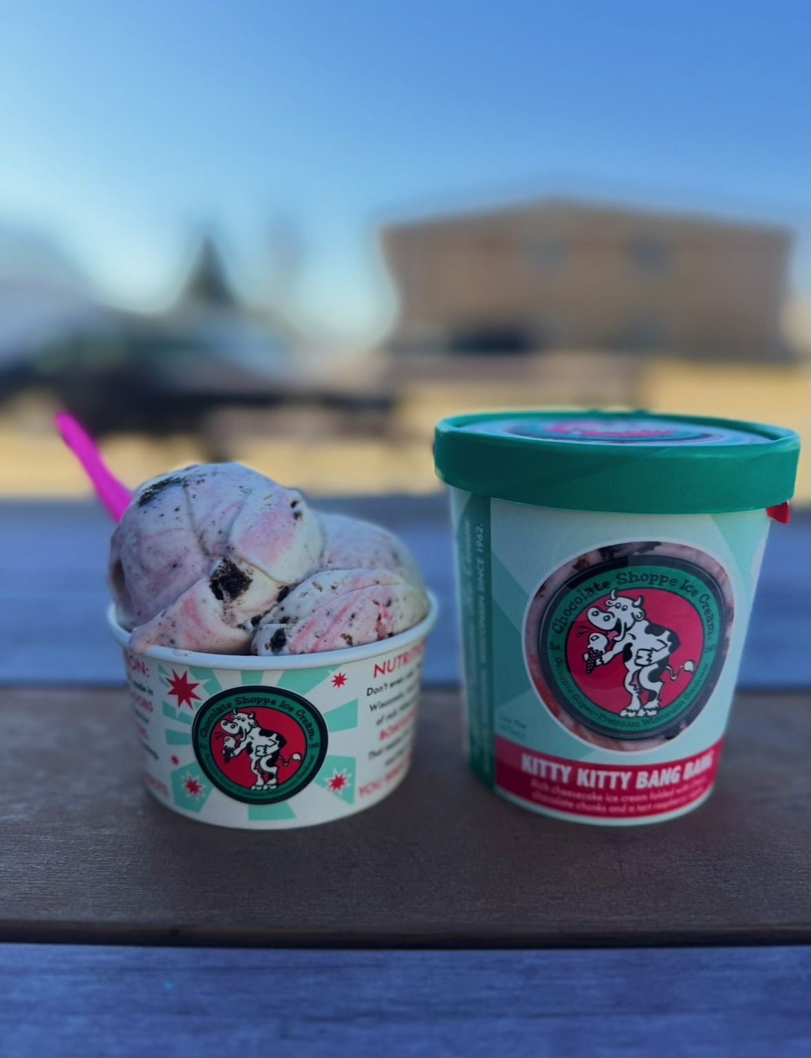 Two cups of ice cream are sitting on a wooden table.