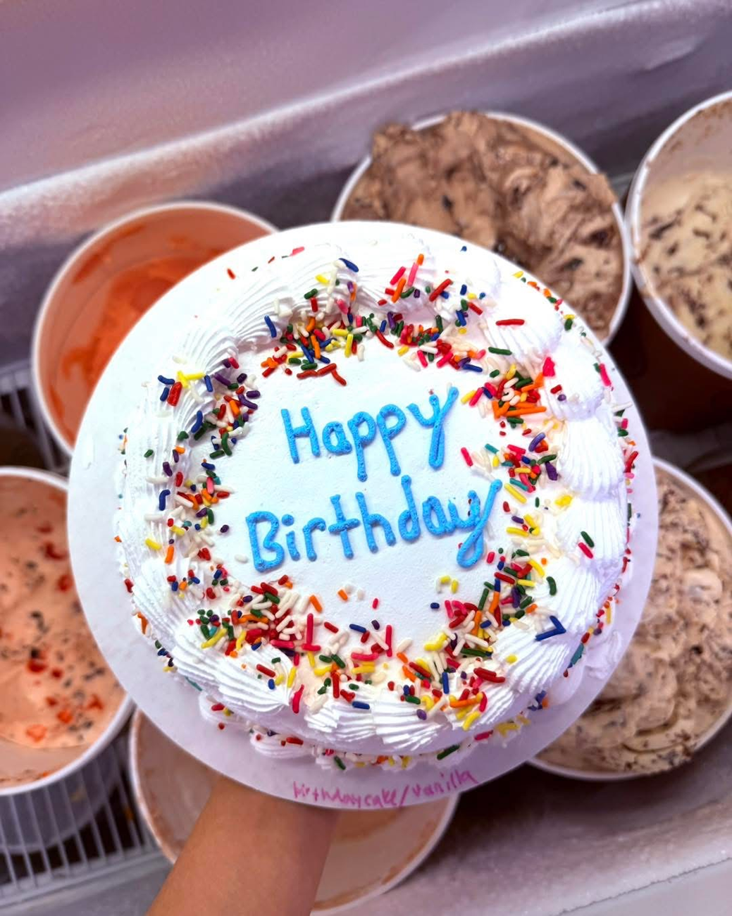 A person is holding a cake that says happy birthday