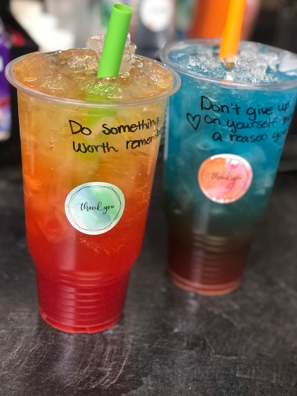 Two cups of drinks with straws and stickers that say do something worth remember