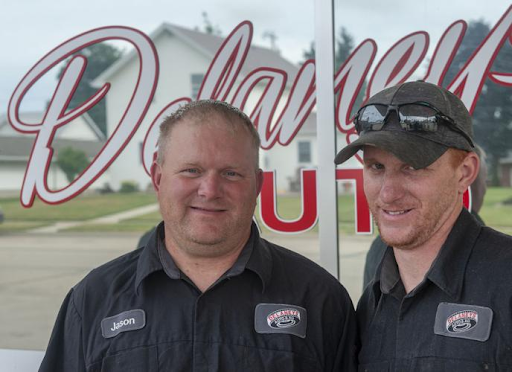 Two men are standing next to each other in front of a window with the word dale on it.