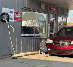 A red car is being charged at a gas station.