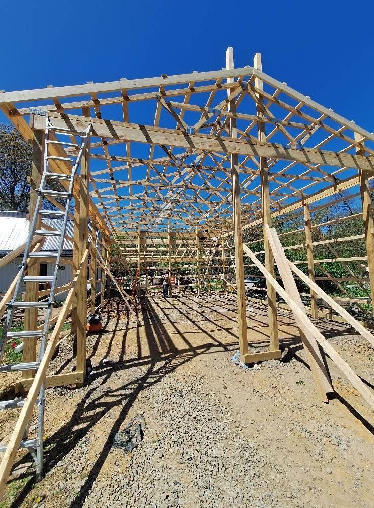 Wooden frame of a building under construction on a sunny day. Ladder and bracing present.