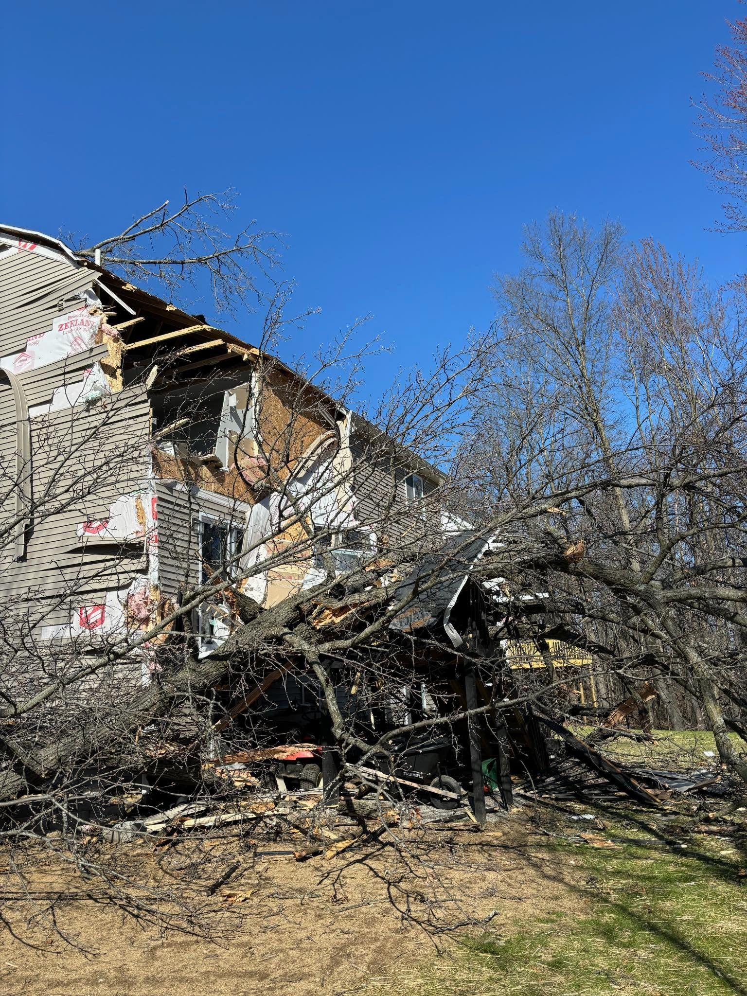 A partially collapsed building with fire damage, under a clear blue sky.